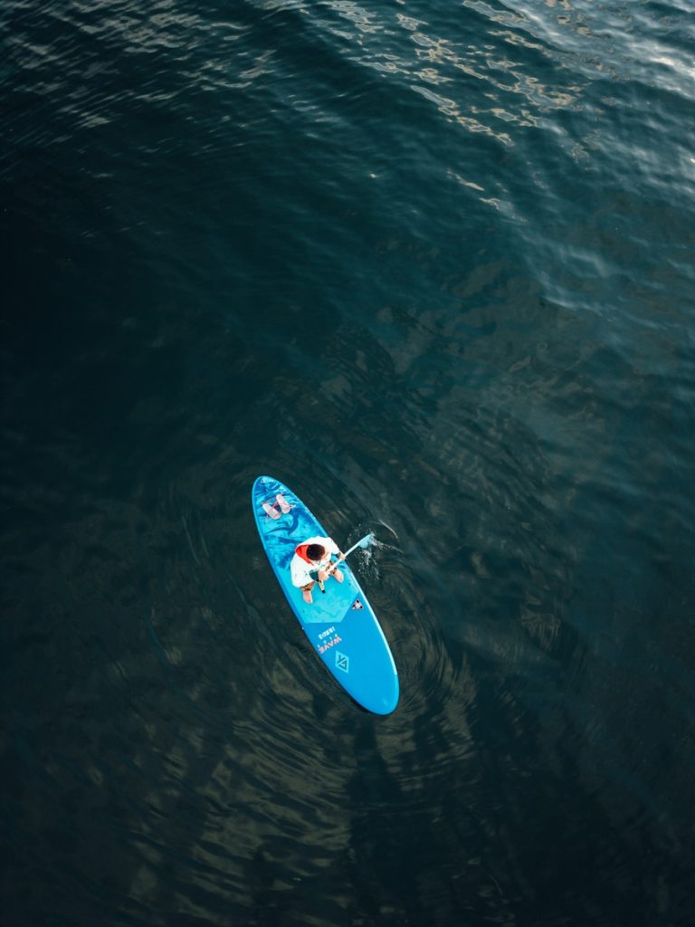 A person paddleboarding on a dark blue ocean.